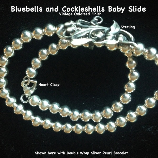 This  pretty and delicate little slide has such detail and femininity. Slip an ecru wired ribbon through this slide and tie it as a choker for a simple, romantic look. Comes with a beautiful ribbon.  Sterling Silver Bluebells and Cockleshells Baby Slide. Part of a beautiful trio of slides which also are beautiful on my Double Wrap Silver Pearls Bracelet.  1-3/8" x 5/8 approximately. Hand made in the USA. Hand Signed.  SILVER PEARLS DOUBLE WRAP BRACELET SOLD SEPARATELY.